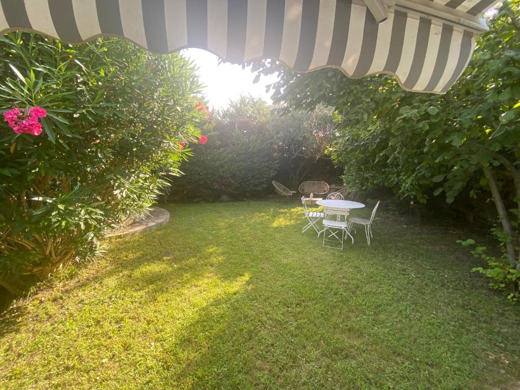 einen Garten mit einem Tisch und Stühlen unter einem Sonnenschirm in der Unterkunft "A Deux Pas de la Montagnette", mazet provencal 4 personnes in Boulbon