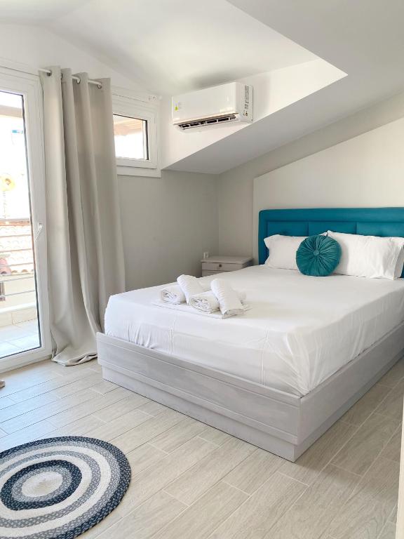 - une chambre avec un grand lit blanc et une tête de lit bleue dans l'établissement Delia Apartments, à Pefkohori