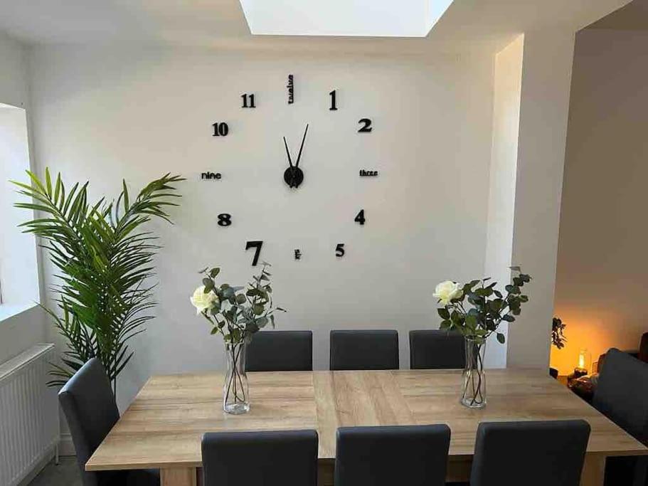 eine große Uhr an einer Wand über einem Tisch in der Unterkunft 5 Bed, easy access to Stratford/Central London in London