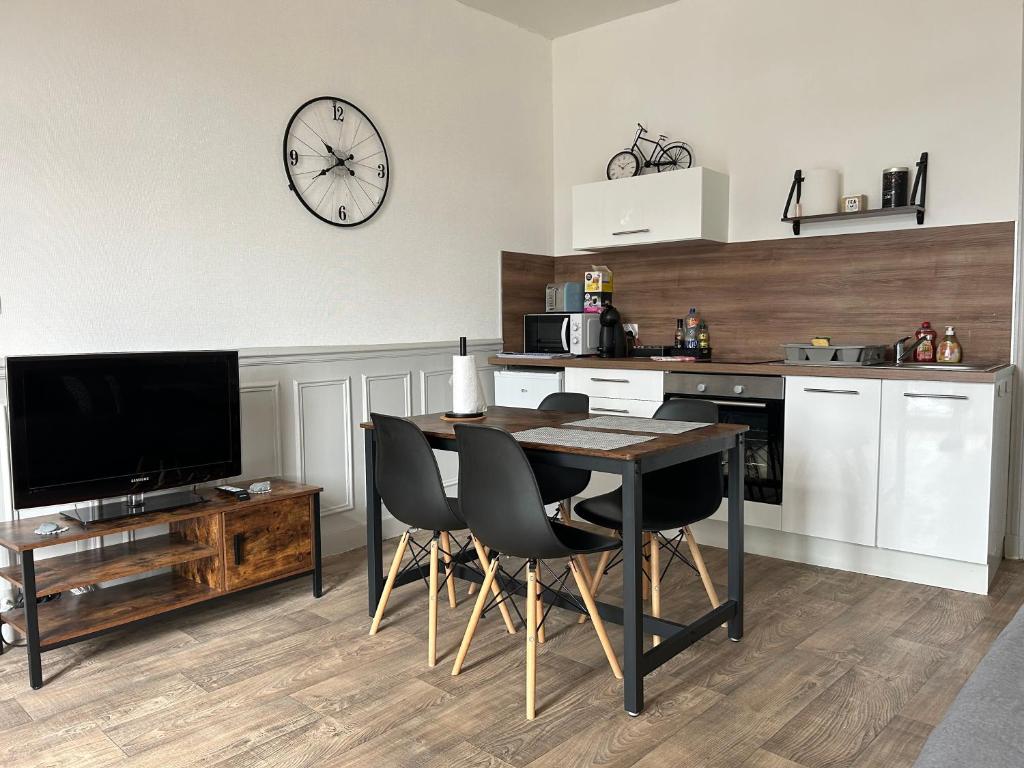 una cocina con mesa y sillas y un reloj en la pared en Appartement F1, refait à neuf, 150m de la plage, en Donville-les-Bains