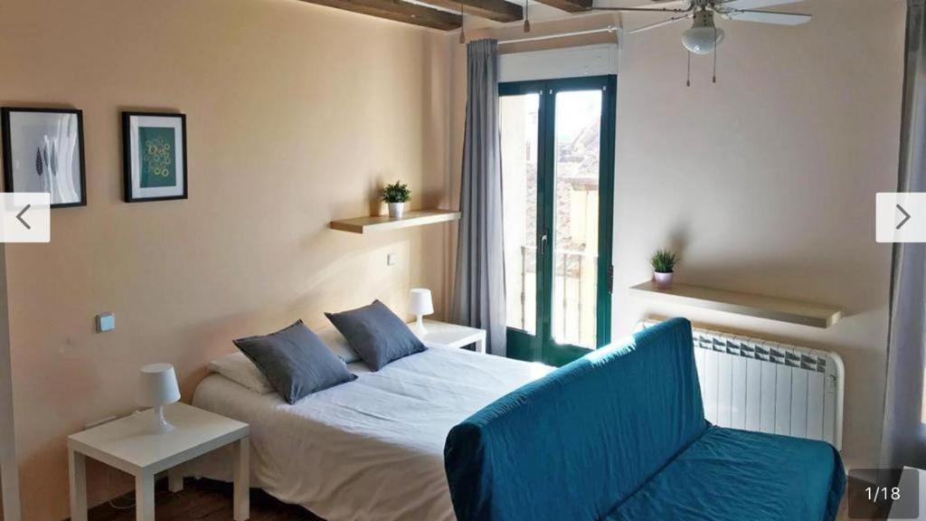 een slaapkamer met een bed, een bank en een raam bij Estudio en Centro de Segovia in Segovia