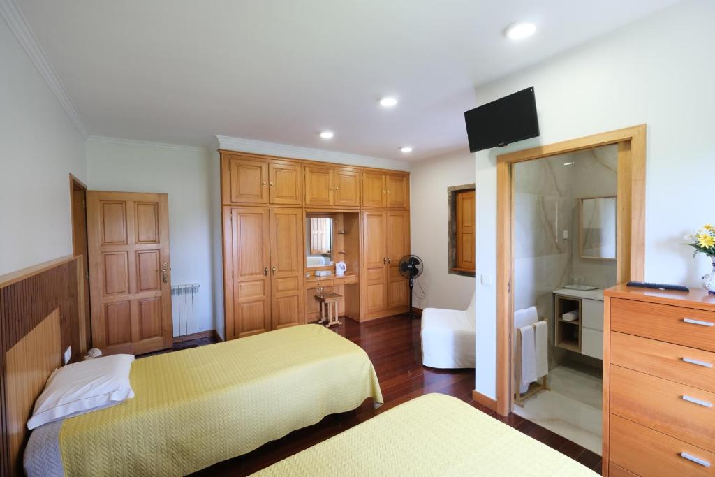 a bedroom with two beds and a television in it at Quintinha d´Avó in Vila de Prado