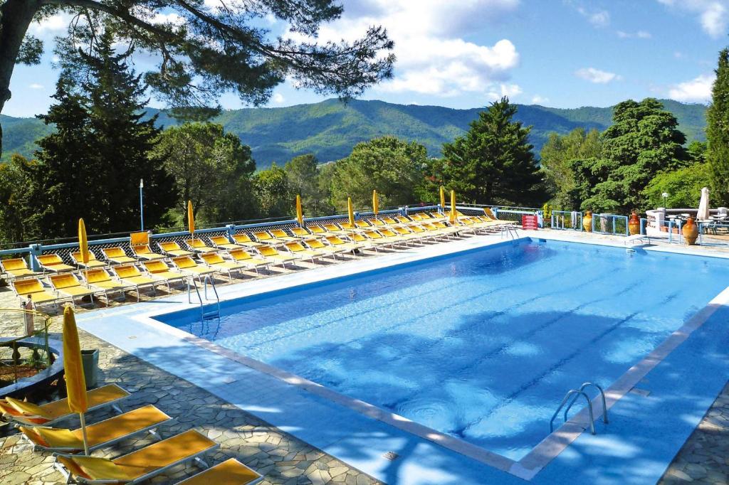 ein großer Pool mit gelben Stühlen und Bergen in der Unterkunft Holiday resort in Villanova d'Albenga in Villanova dʼAlbenga