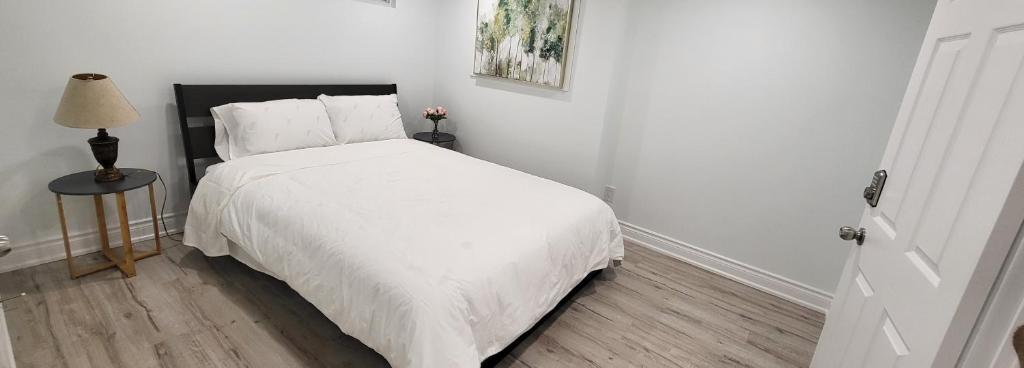 a bedroom with a bed with white sheets and a lamp at Queen Bedroom, Private room, separate entrance 401/404/DVP area in Toronto