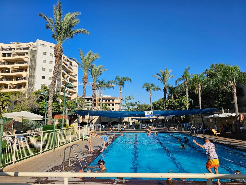 eine Gruppe von Personen in einem Schwimmbad in einem Resort in der Unterkunft A Dream Place in Raanana, Spacious & Luxurious Apartment up to 4 guests - Swimming Pool in Ra‘ananna