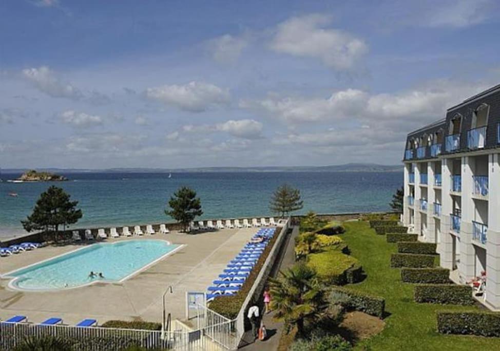 a hotel with a swimming pool next to the ocean at Appartement Douarnenez Résidence en bord de plage in Douarnenez