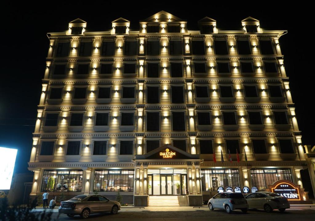 un gran edificio con coches estacionados frente a él en Dastan Grand Hotel, en Jalal-Abad