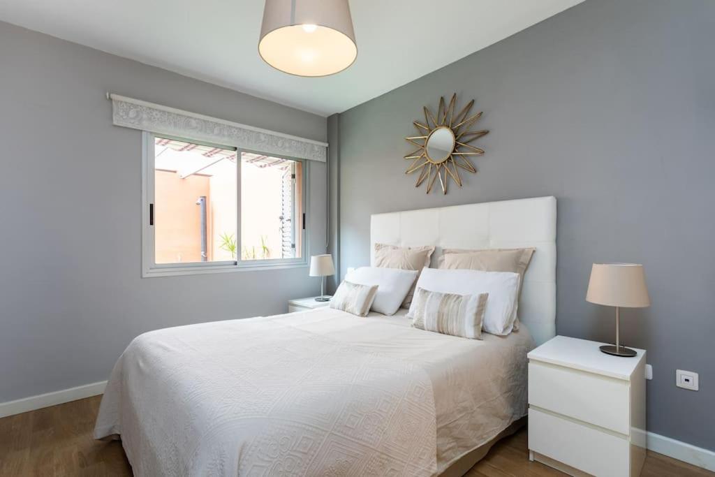 a bedroom with a white bed and a window at Cálido apartamento, piscina, Wi-Fi in Candelaria