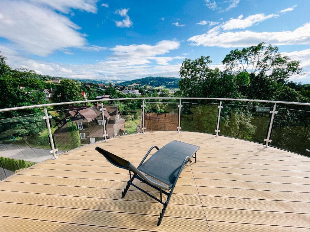 une chaise assise au-dessus d'une terrasse en bois dans l'établissement Penthouse Słoneczna Rapsodia, à Rabka-Zdrój