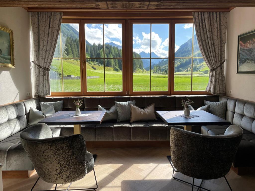 a restaurant with two tables and a couch and a large window at Hotel Montanara in Ischgl
