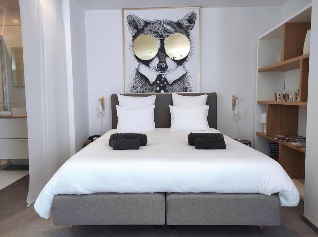 a bedroom with a white bed with a wolf picture on the wall at La planque du raton laveur in Lierneux
