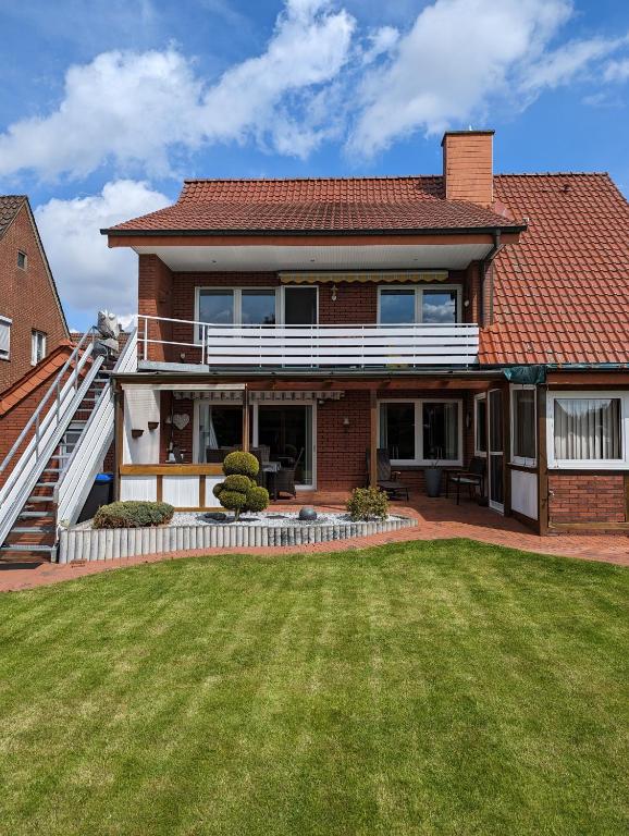 a red brick house with a grass yard at Ferienwohnung Leni erstes OG inkl Balkon Gartenblick kostenfreier Parkplatz stadtnah aber ruhig gelegen in Meppen