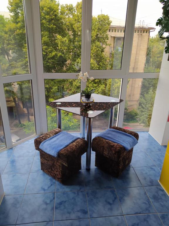 a table and two stools in a room with windows at Центр Апартаменти готель ГРАН in Poltava