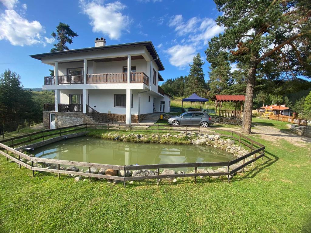 une maison avec un étang en face de celle-ci dans l'établissement Вила Слънчев Бряг, à Dospat