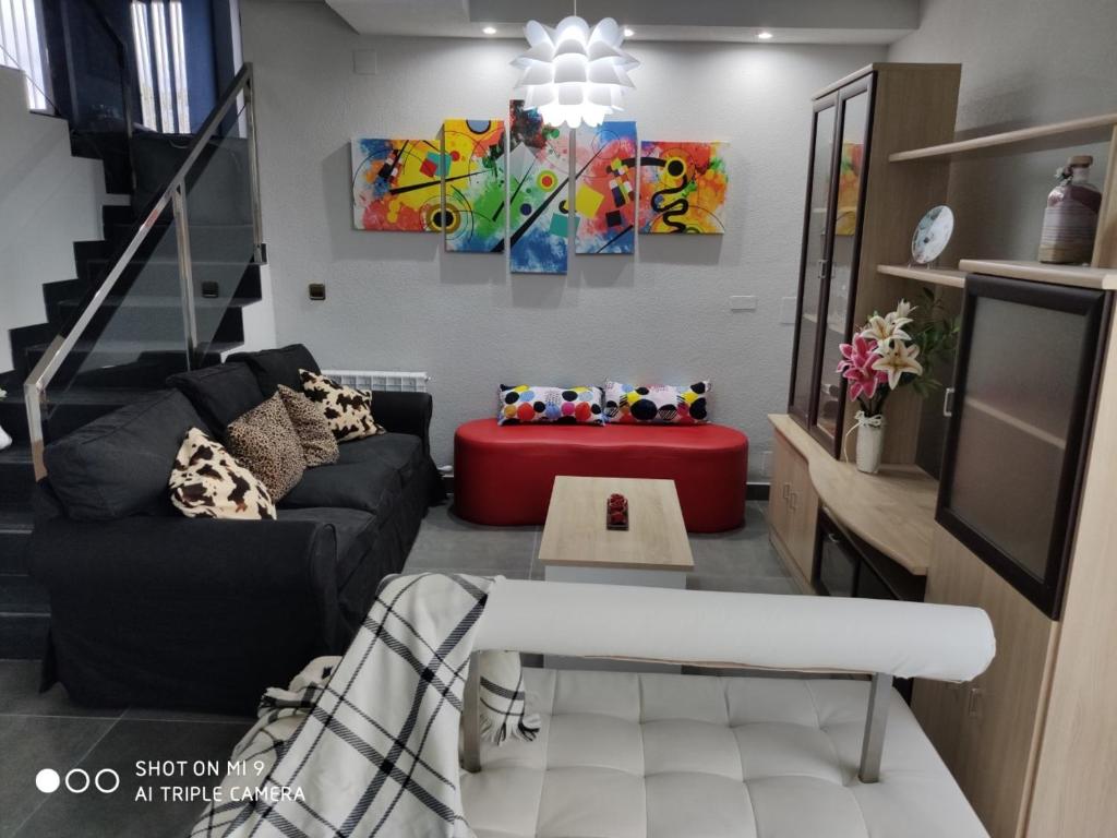 sala de estar con sofá negro y taburete rojo en EL EDEN De SALAMANCA, en Villares de la Reina