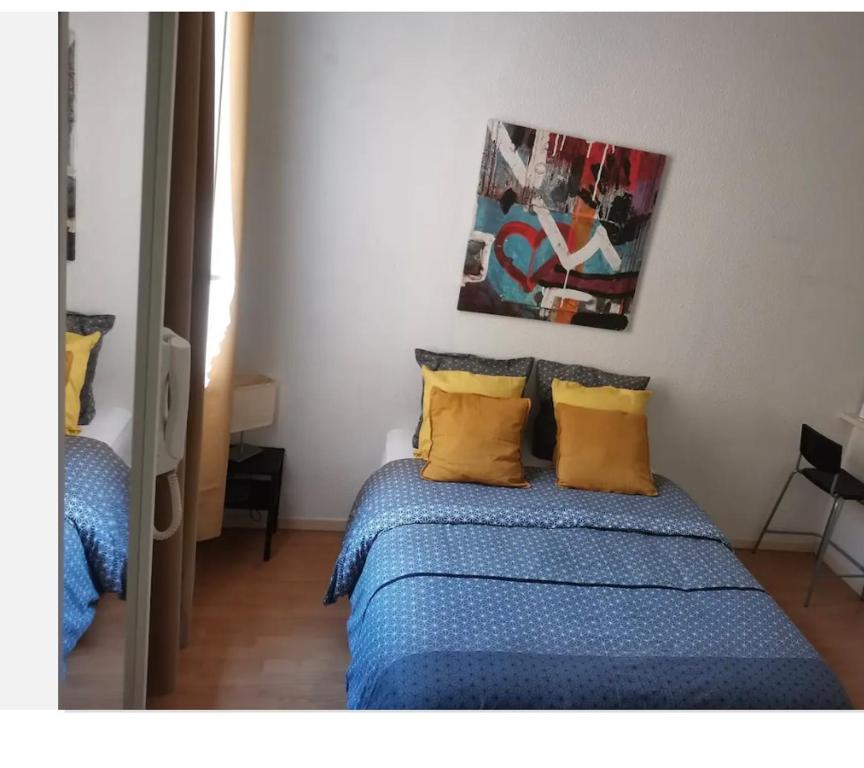 1 dormitorio con 1 cama con sábanas azules y almohadas amarillas en Loux en Lyon