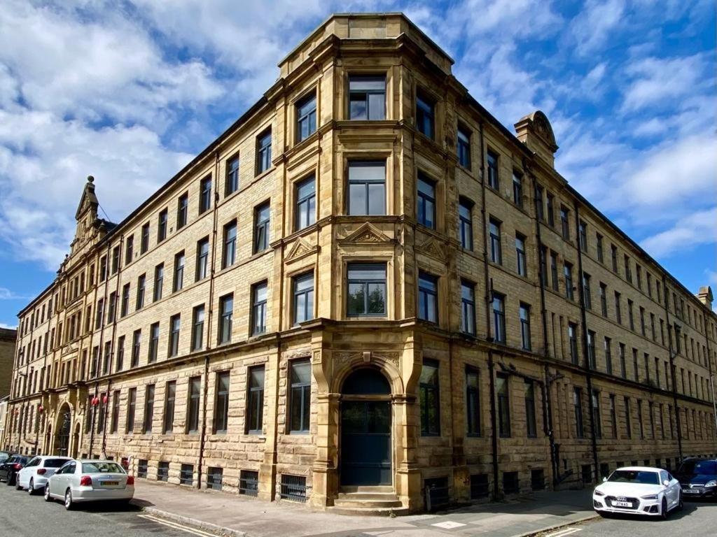 a large stone building with cars parked in front of it at Velvet Apartments - Conditioning House in Bradford