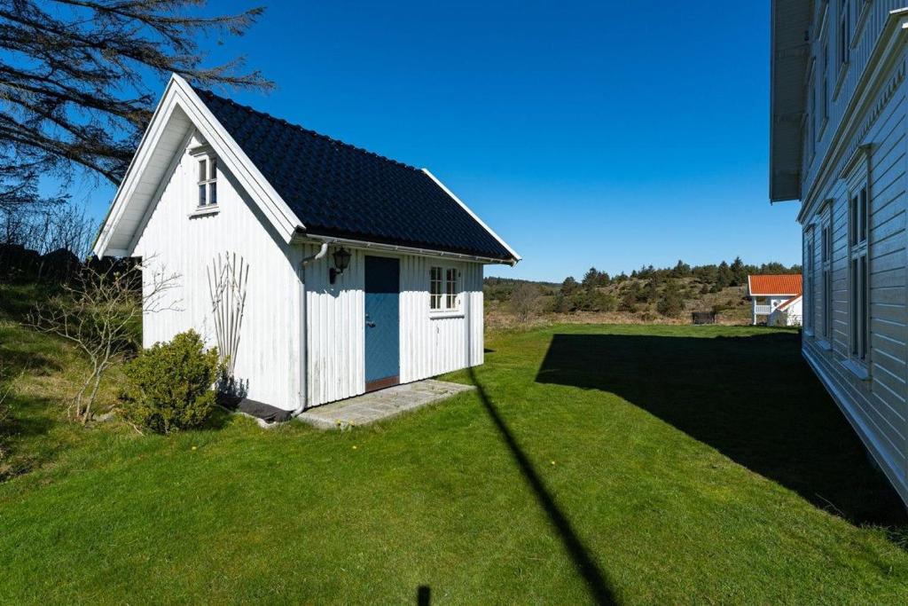 a small white building in a yard next to a house at Villa Krågenes in Farsund