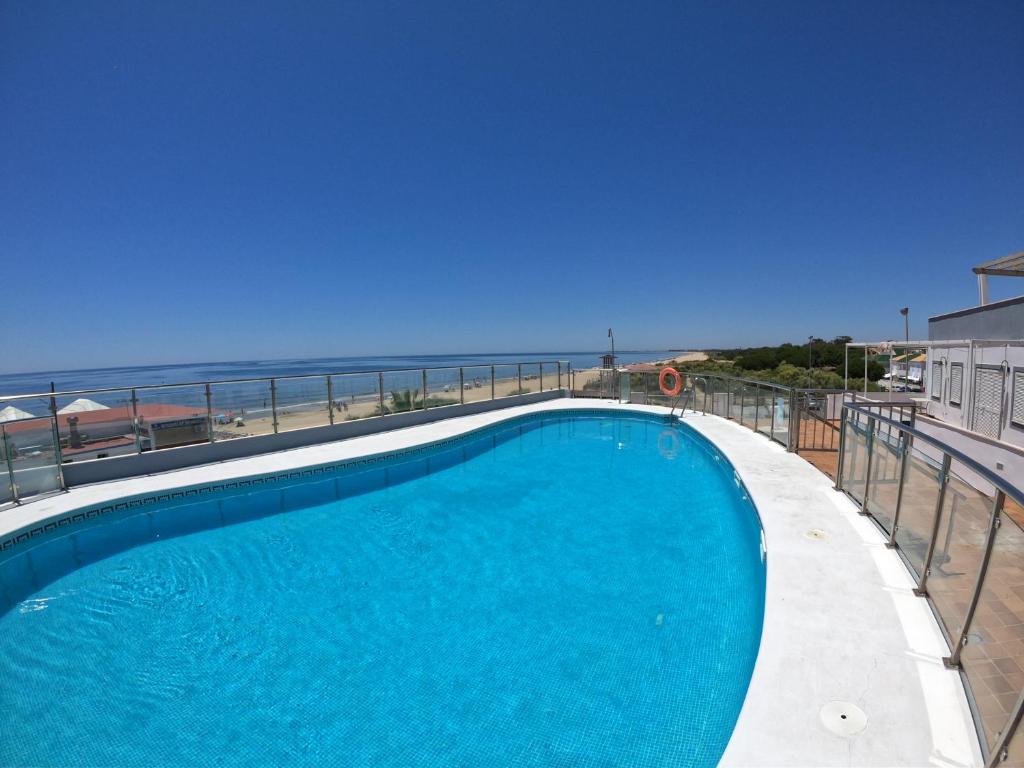 uma piscina com o oceano ao fundo em Islantilla primera linea de playa, piscina, parking na Islantilla