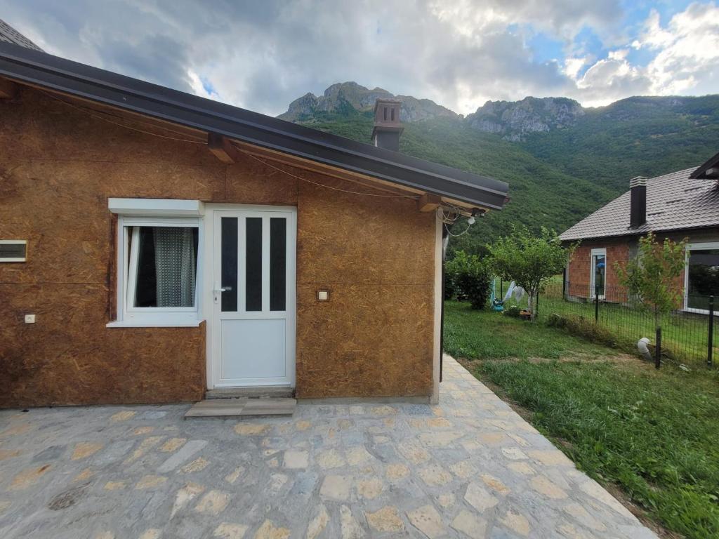 a brick house with a white door with mountains in the background at Lola Guest House in Vusanje