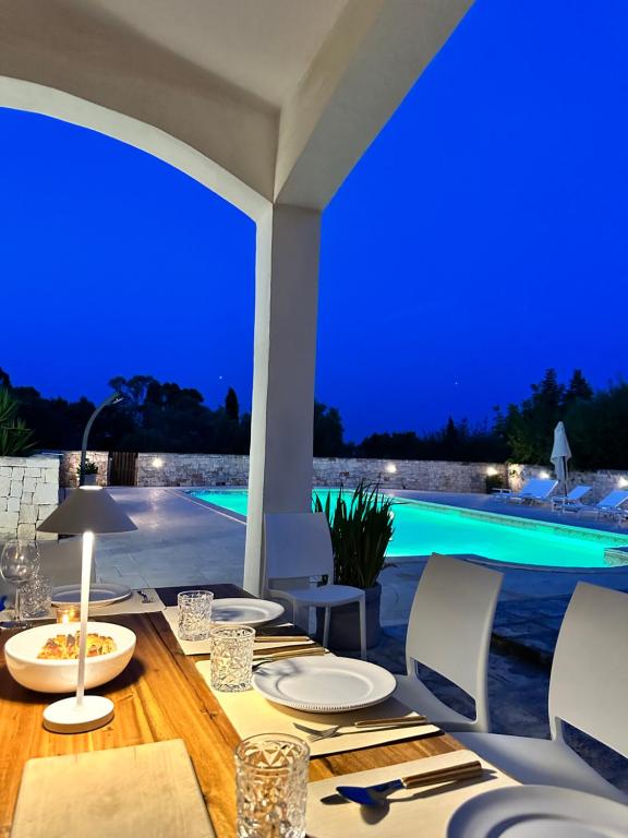 une table à manger et des chaises avec vue sur une piscine dans l'établissement Villa Magis, à Ostuni