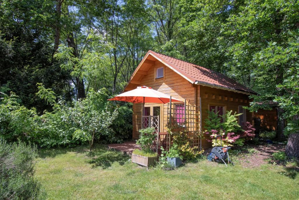 une petite cabine avec un parasol dans une cour dans l'établissement Etaules, Nouvelle-Aquitaine, charmant chalet, à Étaules