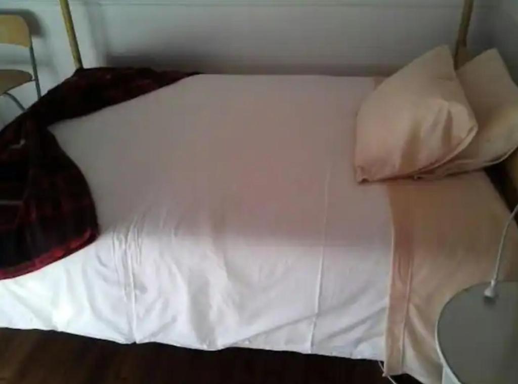 uma cama com lençóis brancos e almofadas num quarto em Sunny Double Room in a Shared Apartment close to Lisbon Downtown em Lisboa