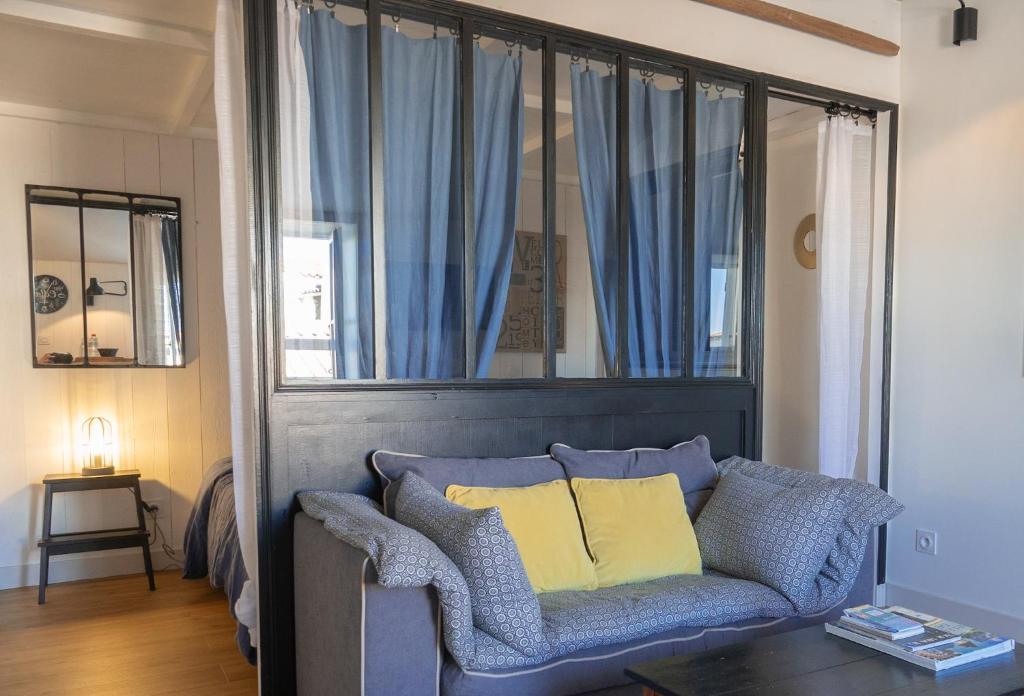 1 sofá azul con 2 almohadas amarillas en la sala de estar en La Martinoise Studio, en Saint-Martin-de-Ré