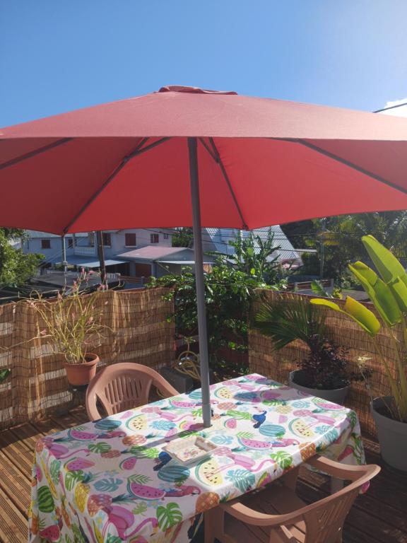 uma mesa com um guarda-chuva vermelho num deque em L escale de bois dO em Saint-Pierre