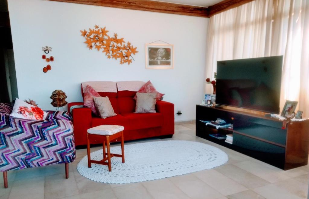 a living room with a red couch and a tv at Quarto em Apto Compartilhado BEIRA MAR in Maceió