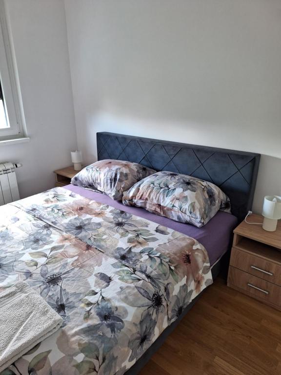 a bedroom with a bed with a floral comforter at Apartman Una banjaluka in Hiseti