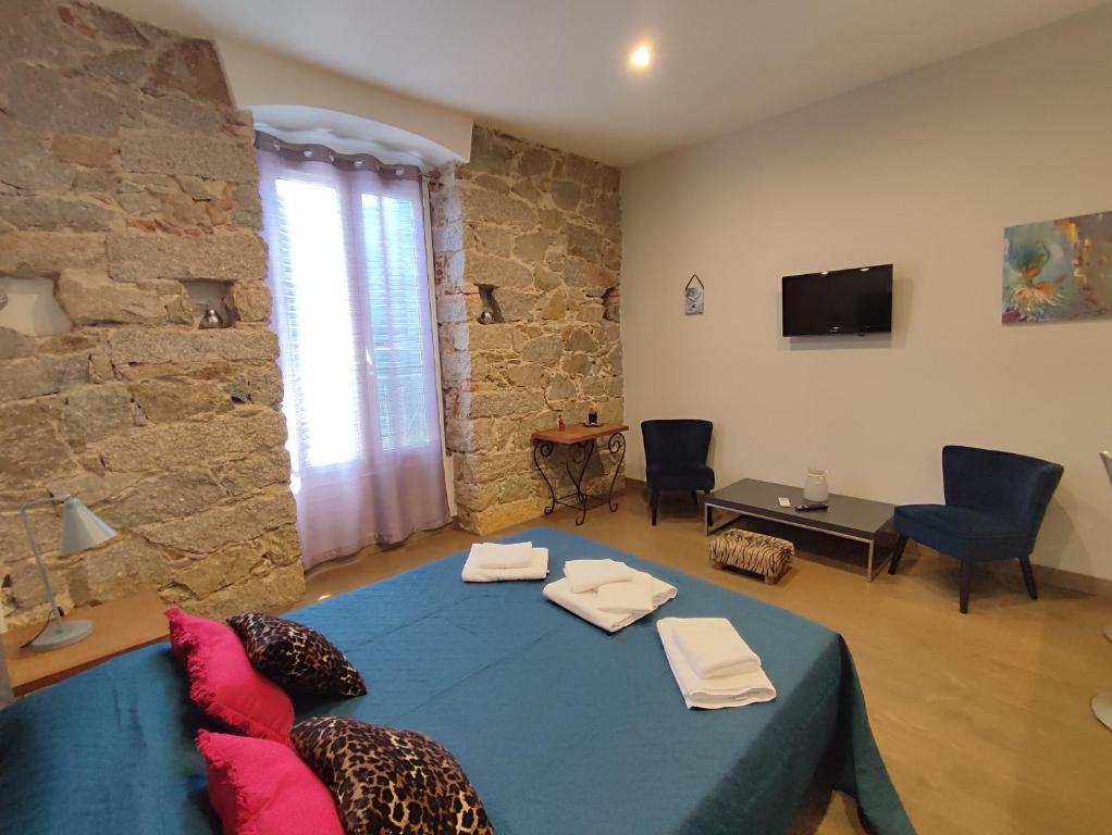 un salon avec une table bleue et un mur en pierre dans l'établissement Studio de 25m2 - Extra centre - À 5 min à pied des plages - Commerces et restaurants sur place - Clim - Wifi - EXCEPTIONNEL, à Ajaccio