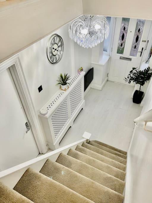 a hallway with stairs and a clock and a chandelier at The Princes Dartford Stunning Entire Space in Kent