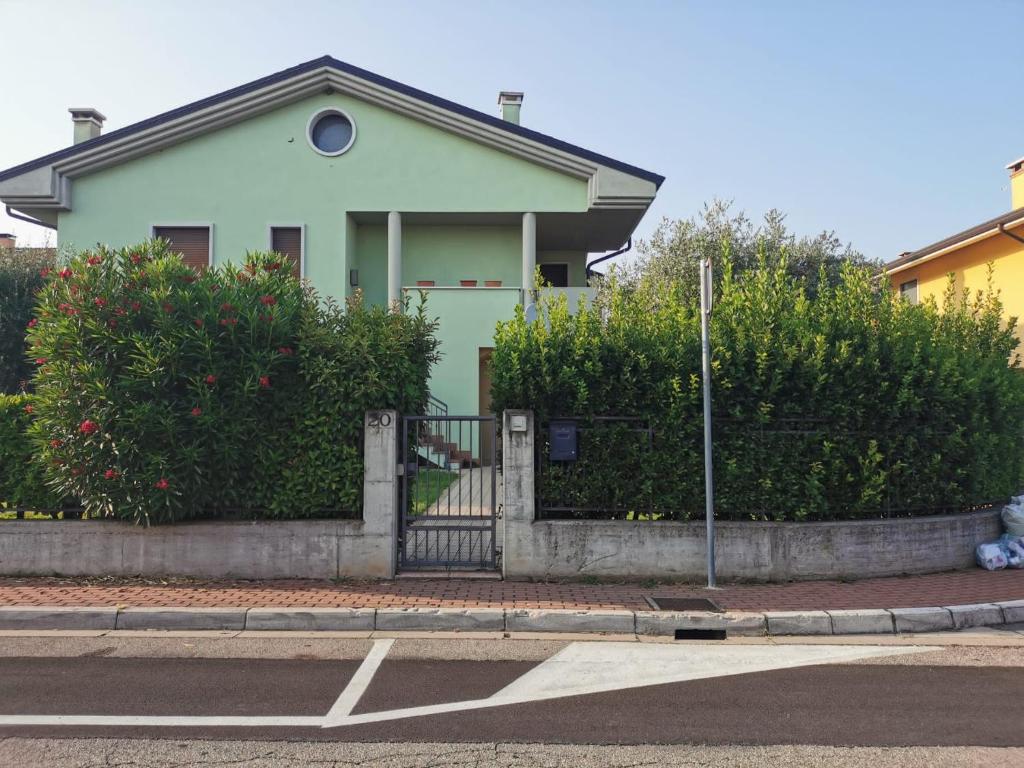 een groen huis met een hek en struiken bij Serenity Home in Posta Vecchia