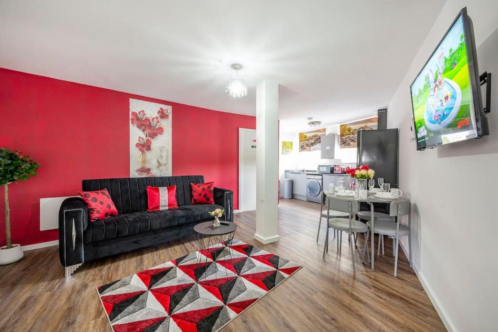 a living room with a black couch and a red wall at *F1BR* for your most relaxed & Cosy stay + Free Parking + Free Fast WiFi in Batley
