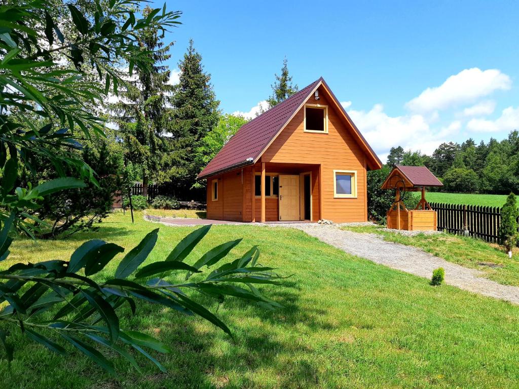 a small house in a grassy yard with a fence at Domki na granicy in Jeżowski Dział