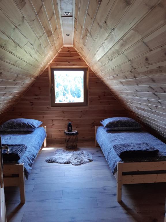 een slaapkamer op zolder met 2 bedden en een raam bij Domki na granicy 