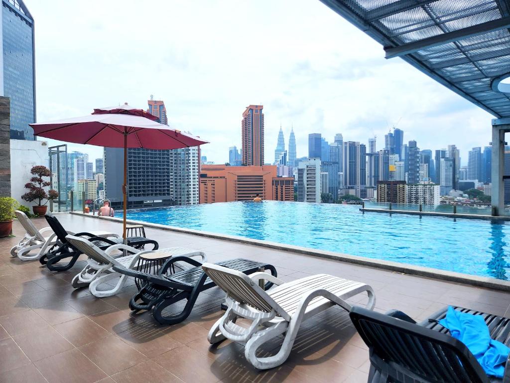 einem Pool mit Stühlen und einem Regenschirm auf einem Gebäude in der Unterkunft Infini Suites@ D'Majestic Place Kuala Lumpur in Kuala Lumpur