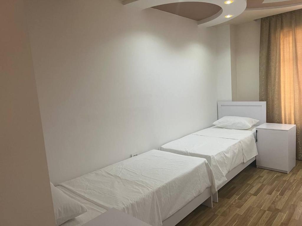 een witte slaapkamer met 2 bedden en een raam bij ZahroSulton in Samarkand