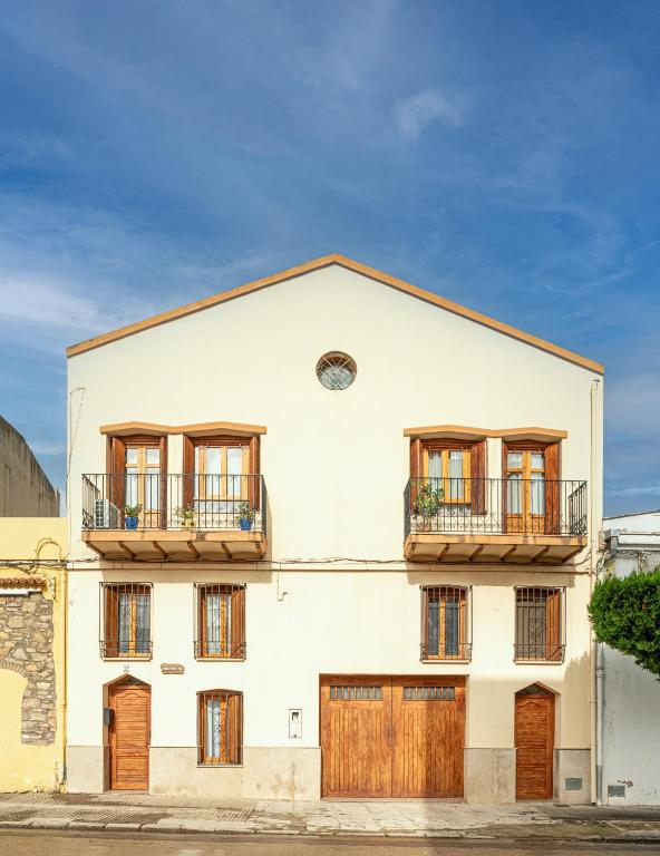 a white building with wooden doors and windows at Casa Rural l'Olivera - Ideal para Retiros, Familias y Amigos - Cerca de Morella y Peñíscola - Mínimo 2 noches in Sant Mateu