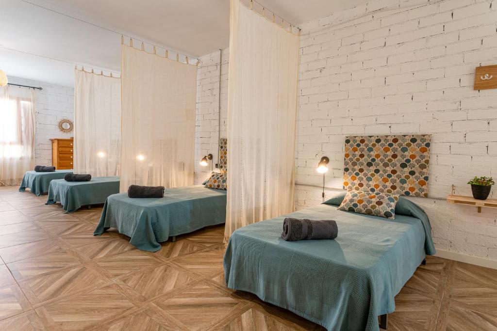una camera con tre letti in una stanza con pareti bianche di Casa Rural l'Olivera - Ideal para Retiros, Familias y Amigos - Cerca de Morella y Peñíscola - Mínimo 2 noches a San Mateo