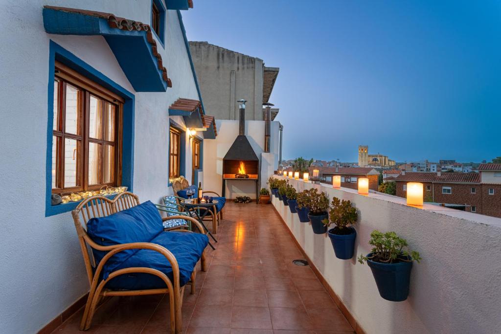 Un balcón con sillas y mesas en un edificio en Casa Rural l'Olivera en Sant Mateu, cerca de Morella y Peñíscola - Casa Completa - Mínimo 2 noches, en Sant Mateu
