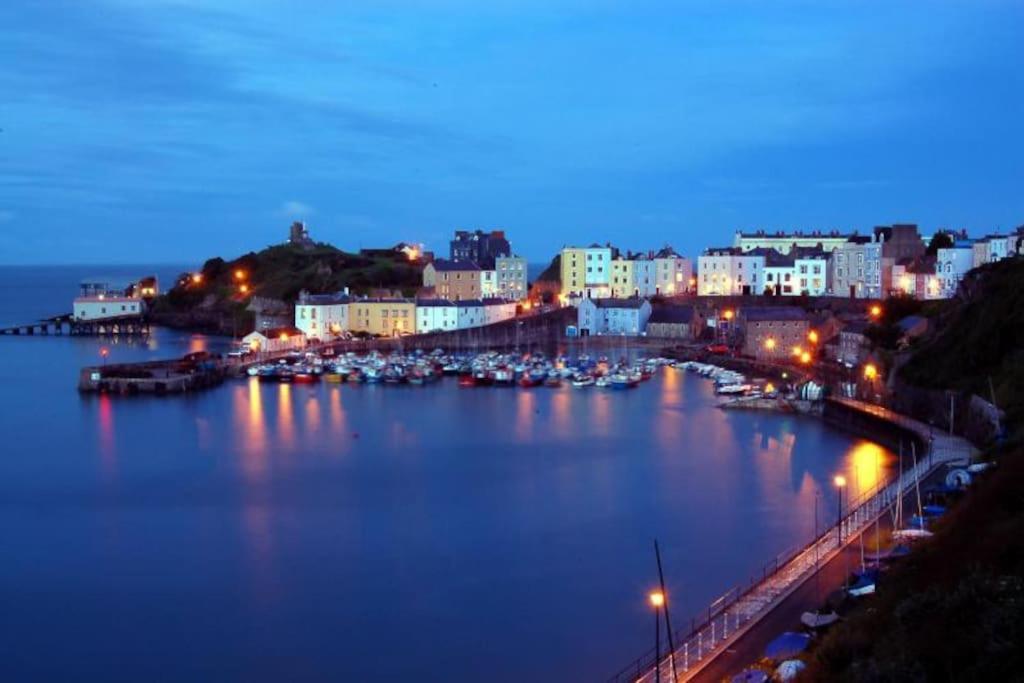 a view of a harbor at night with boats in the water at The beautifully central Flat 3 The Cobourg Tenby in Pembrokeshire