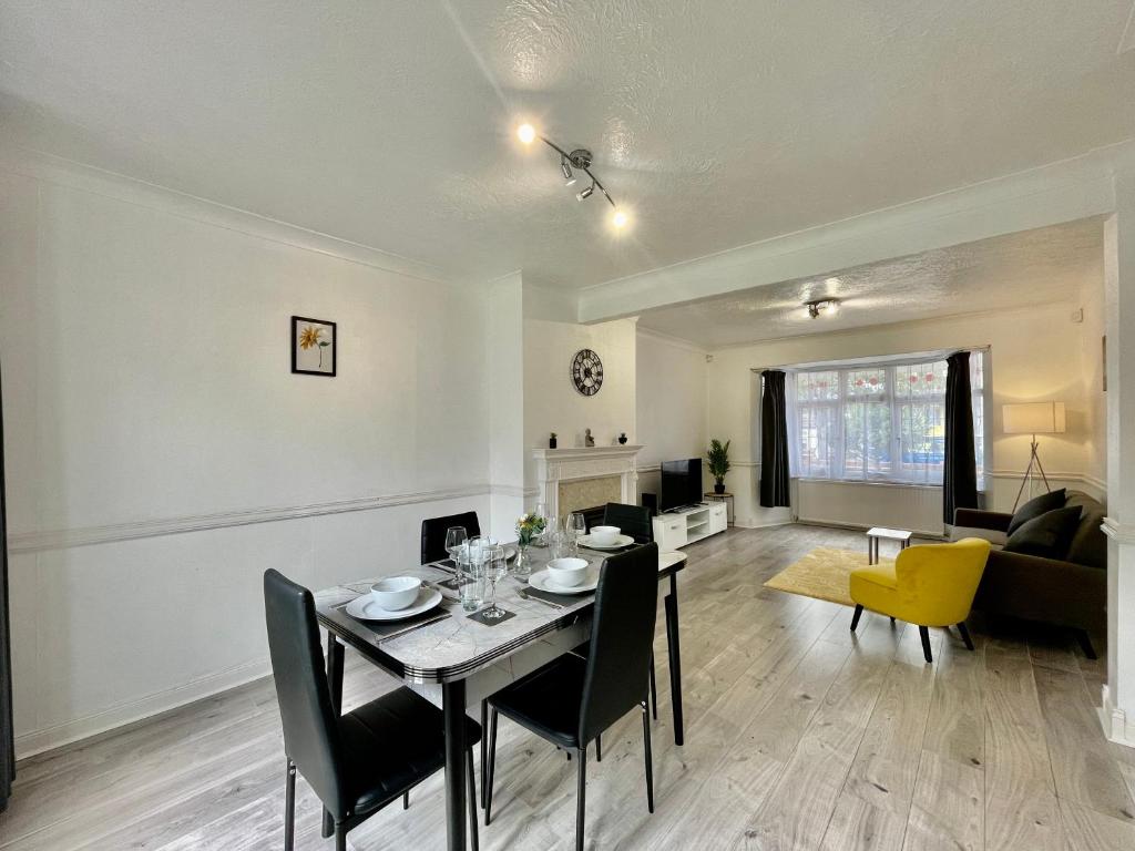 uma sala de jantar e sala de estar com mesa e cadeiras em Modern 4 Bed Romford Home - Free Parking em Great Warley Street