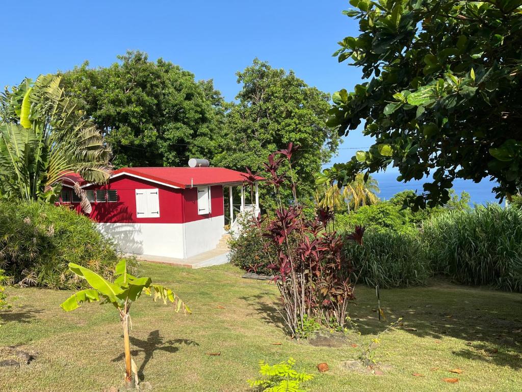 ein rotes und weißes Haus in einem Garten in der Unterkunft Grand bungalow avec piscine et vue mer in Bouillante