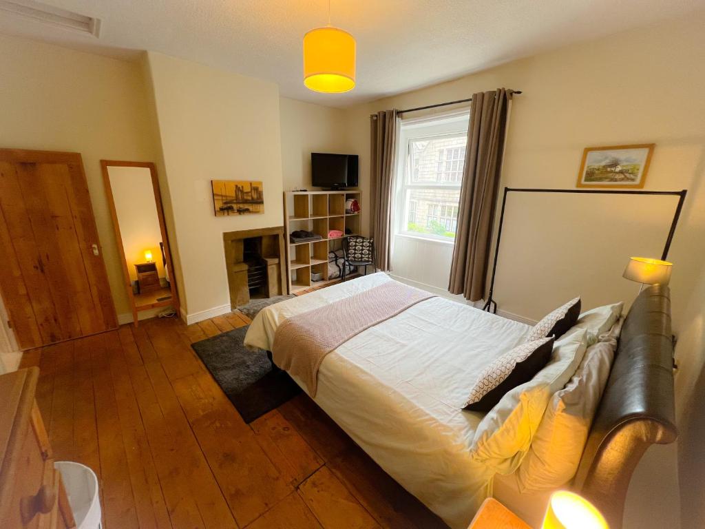 a bedroom with a large bed and a fireplace at Rural Yorkshire Getaway - Modern Victorian Cottage, Long term stay offers, message direct in Luddenden Foot