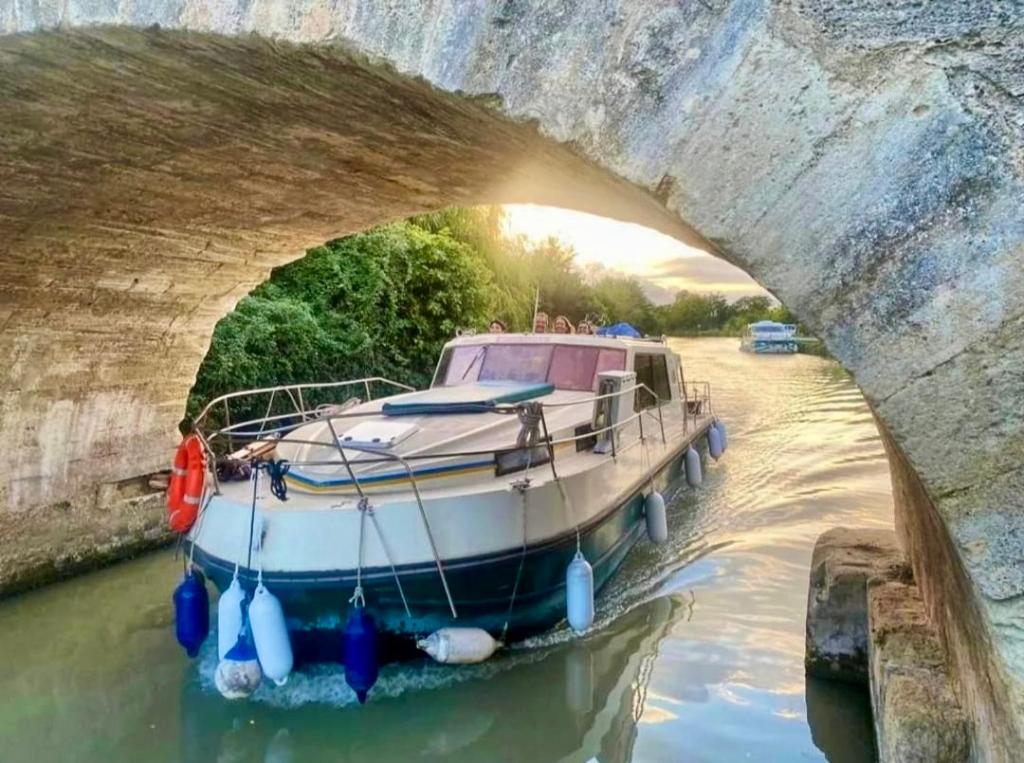 un bateau dans l'eau sous un pont dans l'établissement 1 ou 2 chambres cosy sur une charmante pénichette de 11 m - Pour plus de détails, veuillez consulter notre profil, à Marseillan