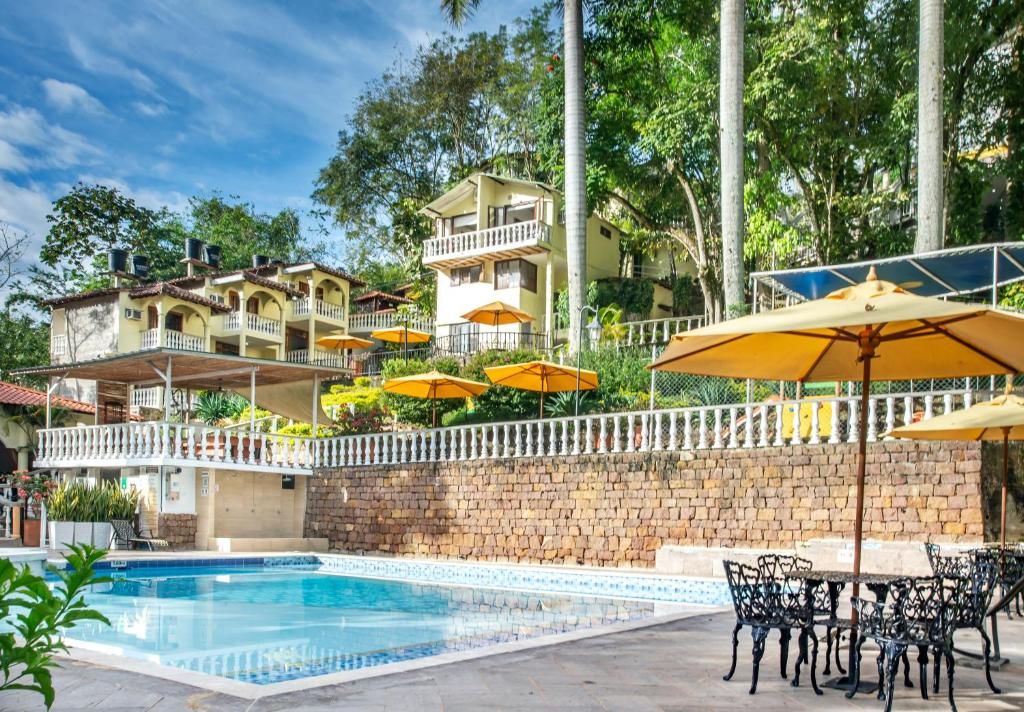 a pool with chairs and umbrellas and a building at Hotel Posada Campestre San Gil in San Gil