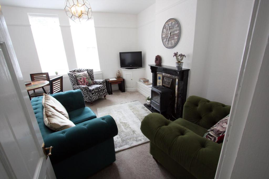a living room with two green chairs and a fireplace at Lymm Village Apartment in Lymm