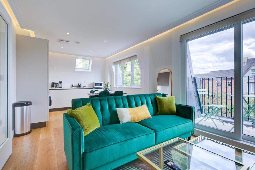 sala de estar con sofá verde y cocina en Stylish Apt with Balcony and easy central access, en Londres